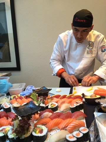 Chef Cisco slicing ingredients beside a finished sushi display