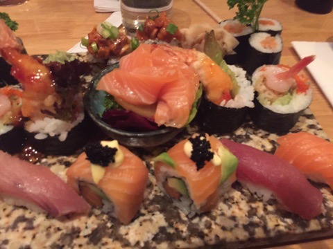 Salmon sashimi, nigiri and speciality rolls on a stone platter