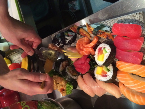 A chef shaping wasabi beside salmon, tuna and maki
