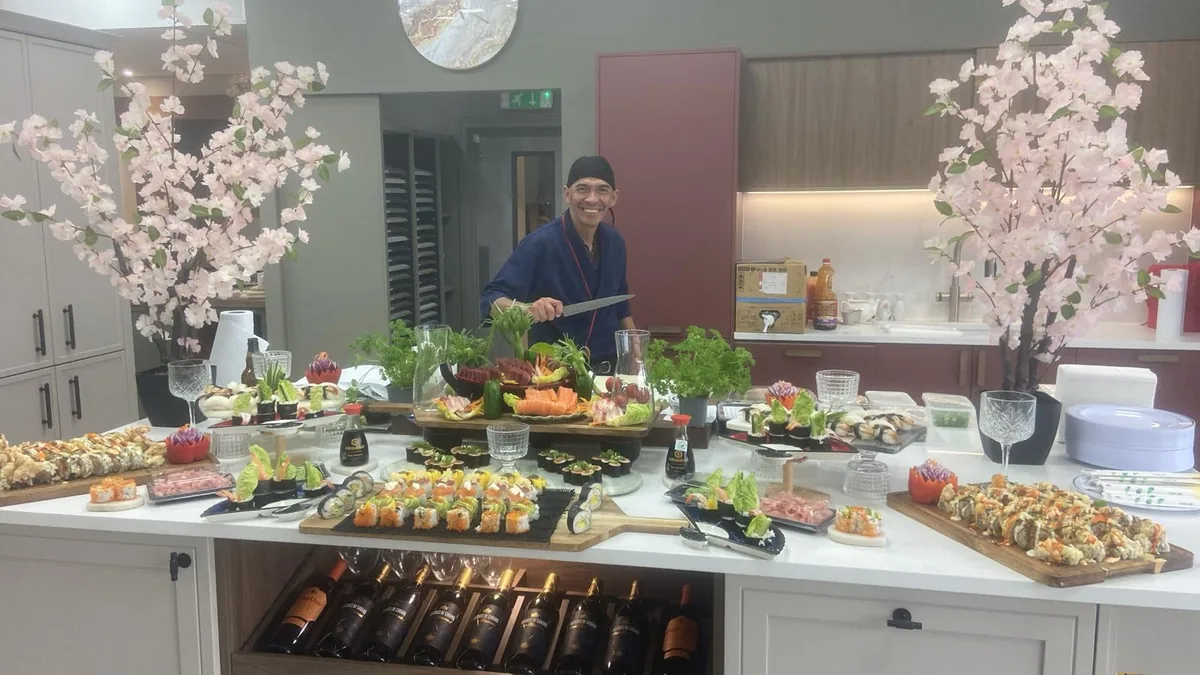 Chef Cisco smiling behind a completed sushi display at a private event